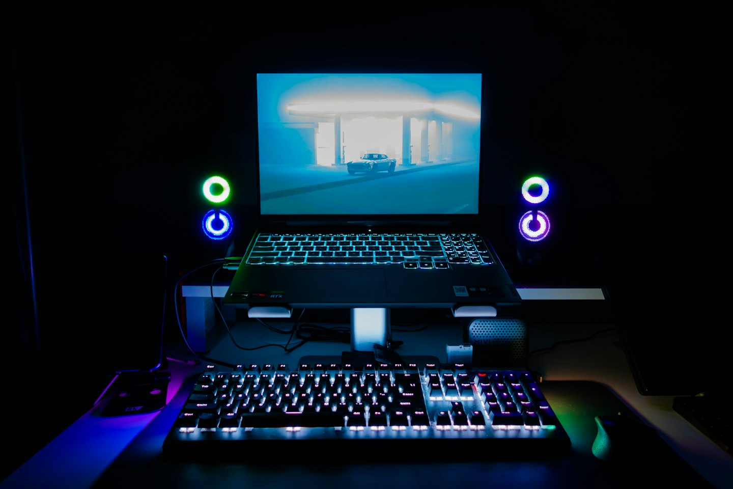 Modern gaming setup with RGB illuminated laptop and keyboard.