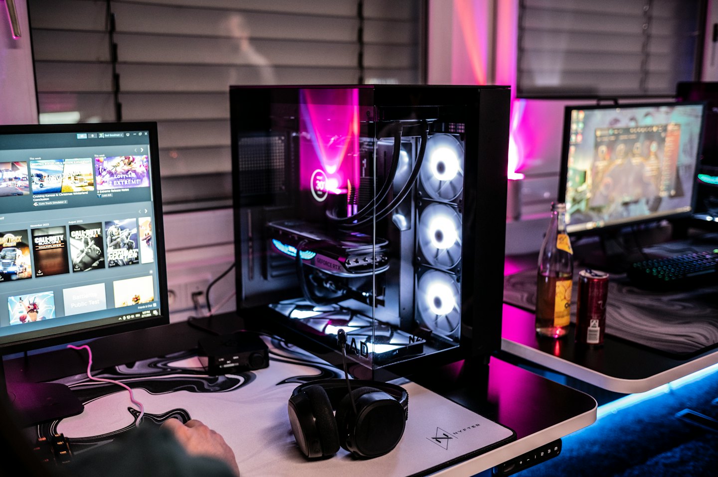 Hand using a gaming mouse next to a glowing PC tower.