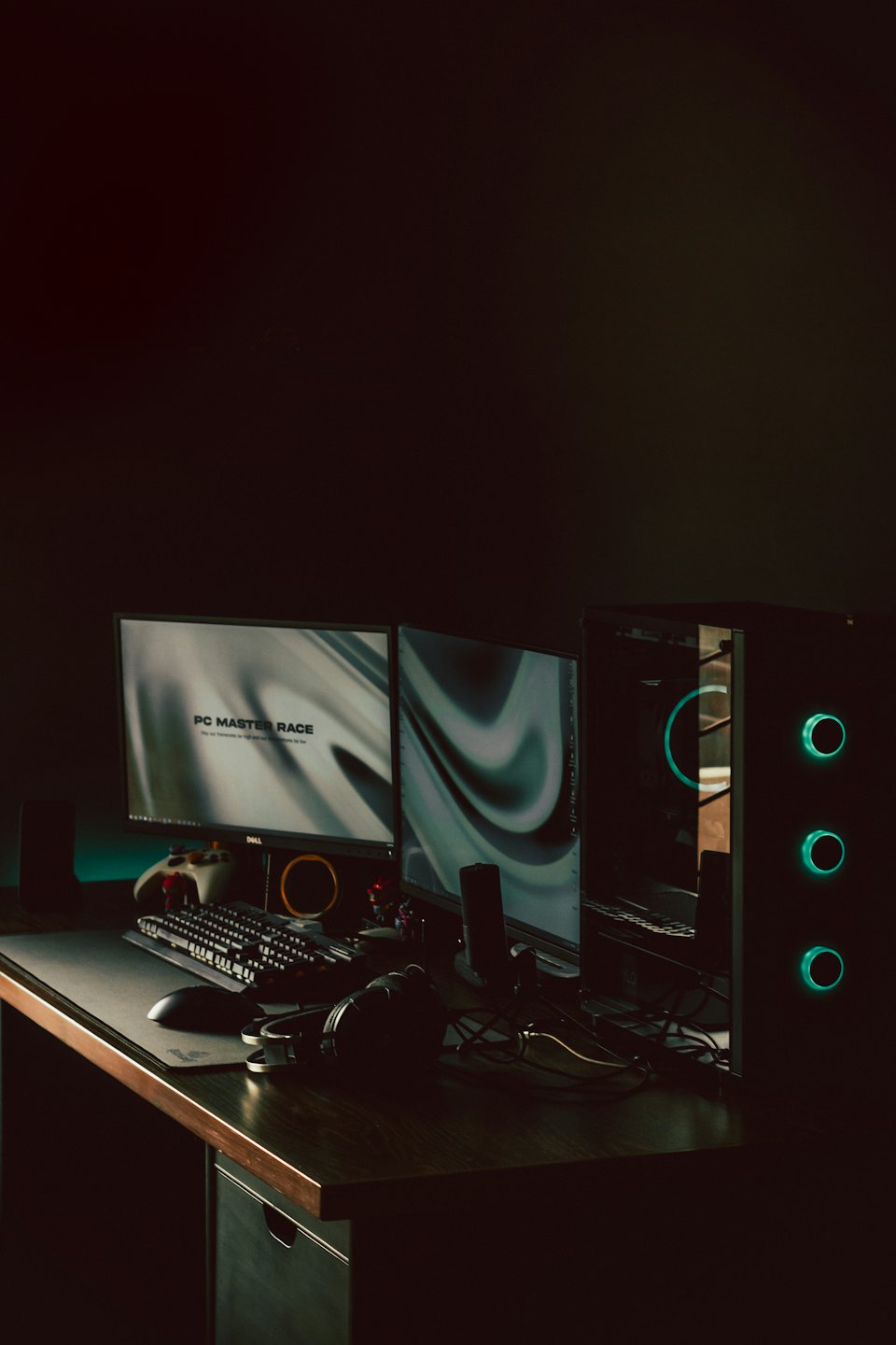 Two monitors display abstract graphics on a dark wooden desk.